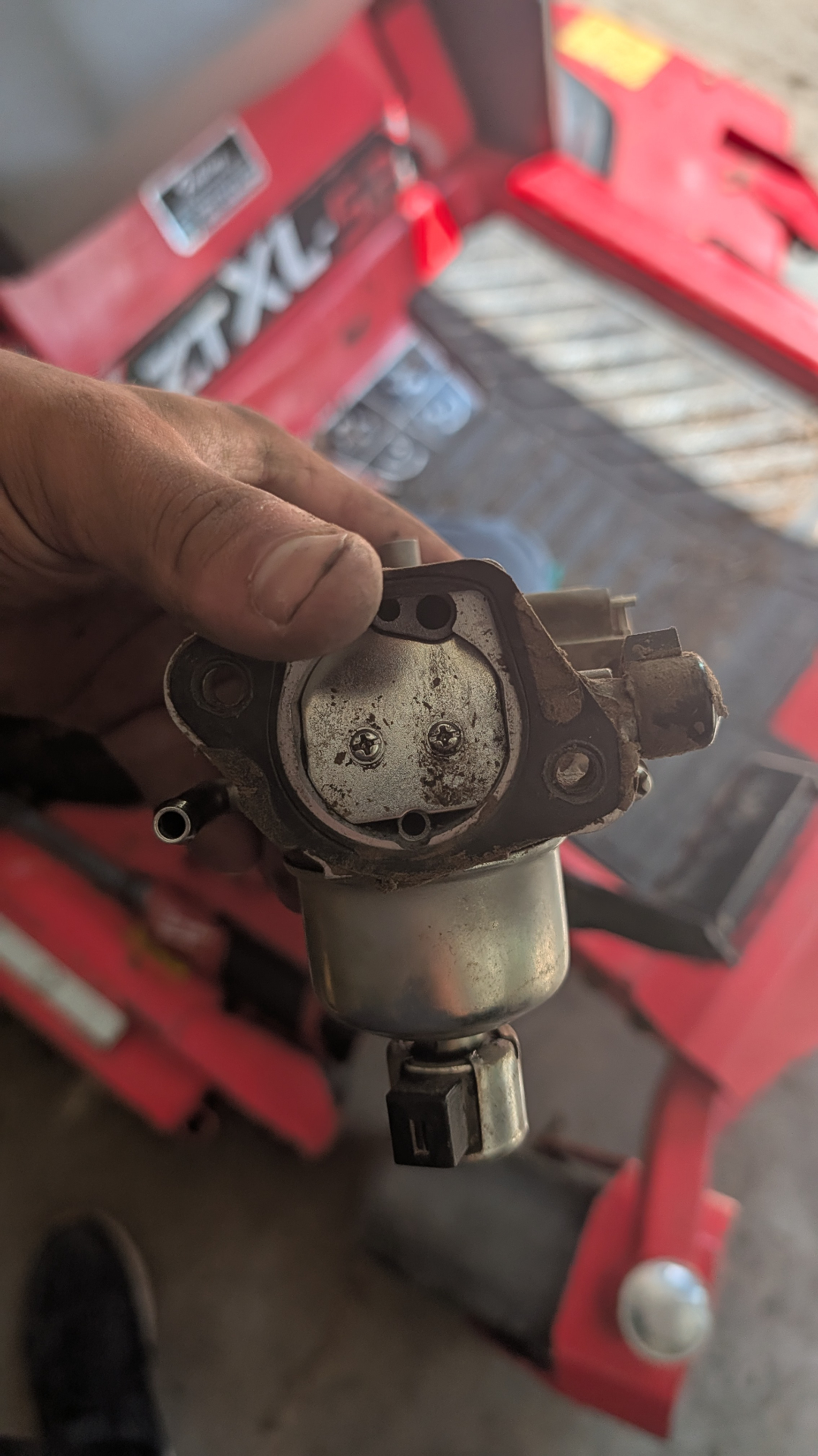 Carburetor removed from a mower engine, held in hand