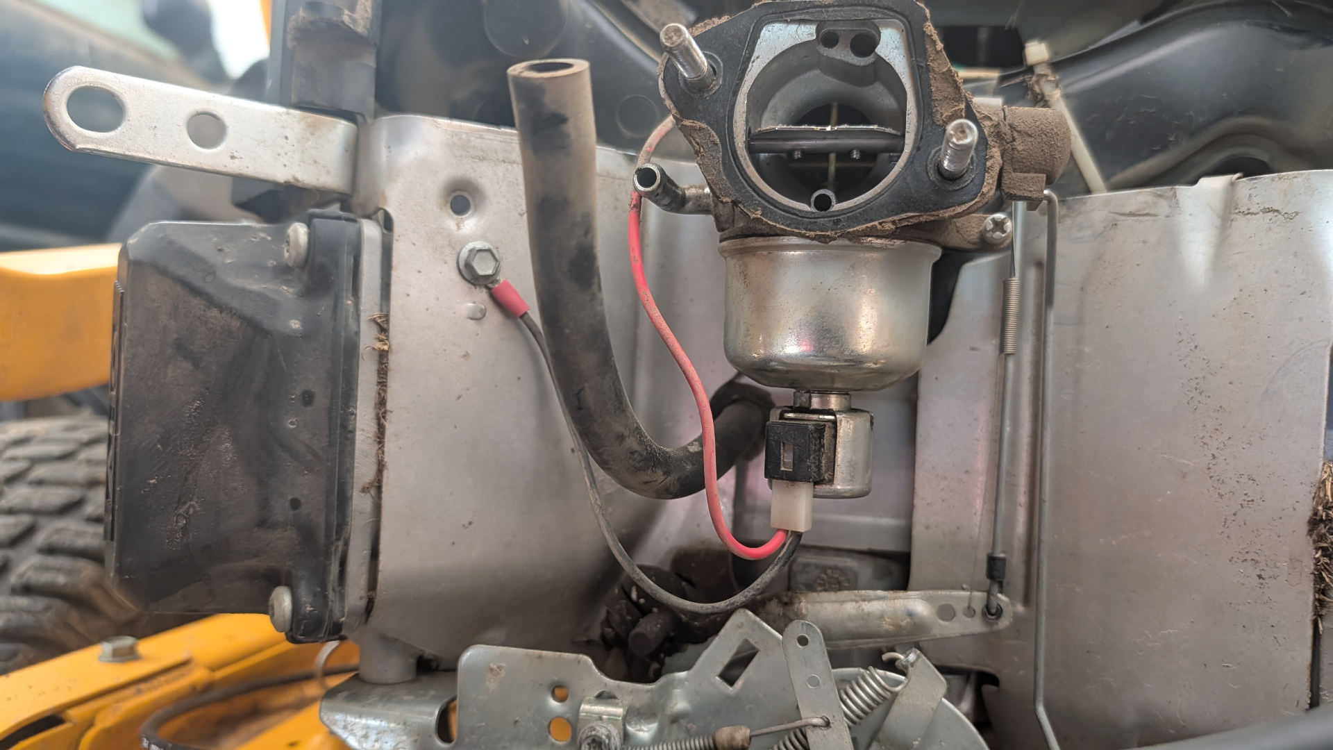 Carburetor mounted on a mower engine with fuel solenoid wiring