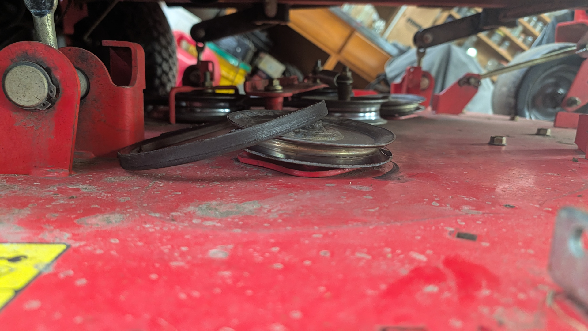 Spindle pulleys and belt under a red mower deck